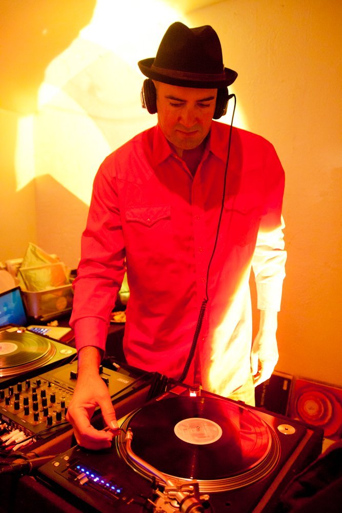 Goyo at the decks in a fedora and headphones