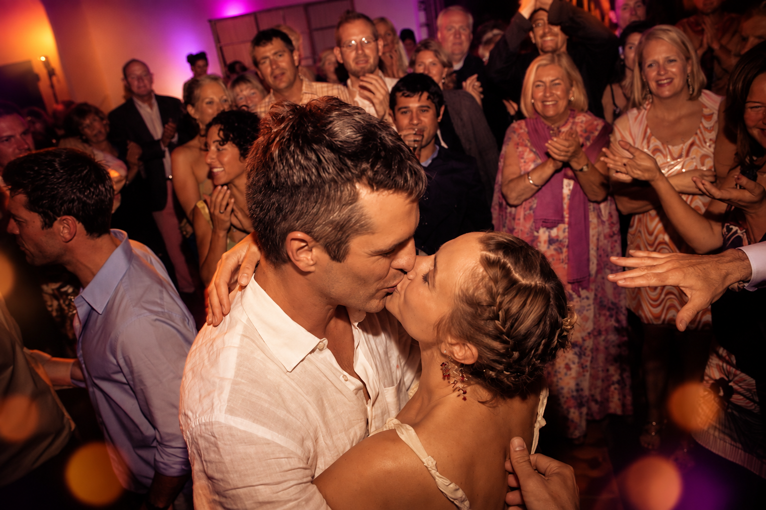 A couple kissing on a packed dance floor
