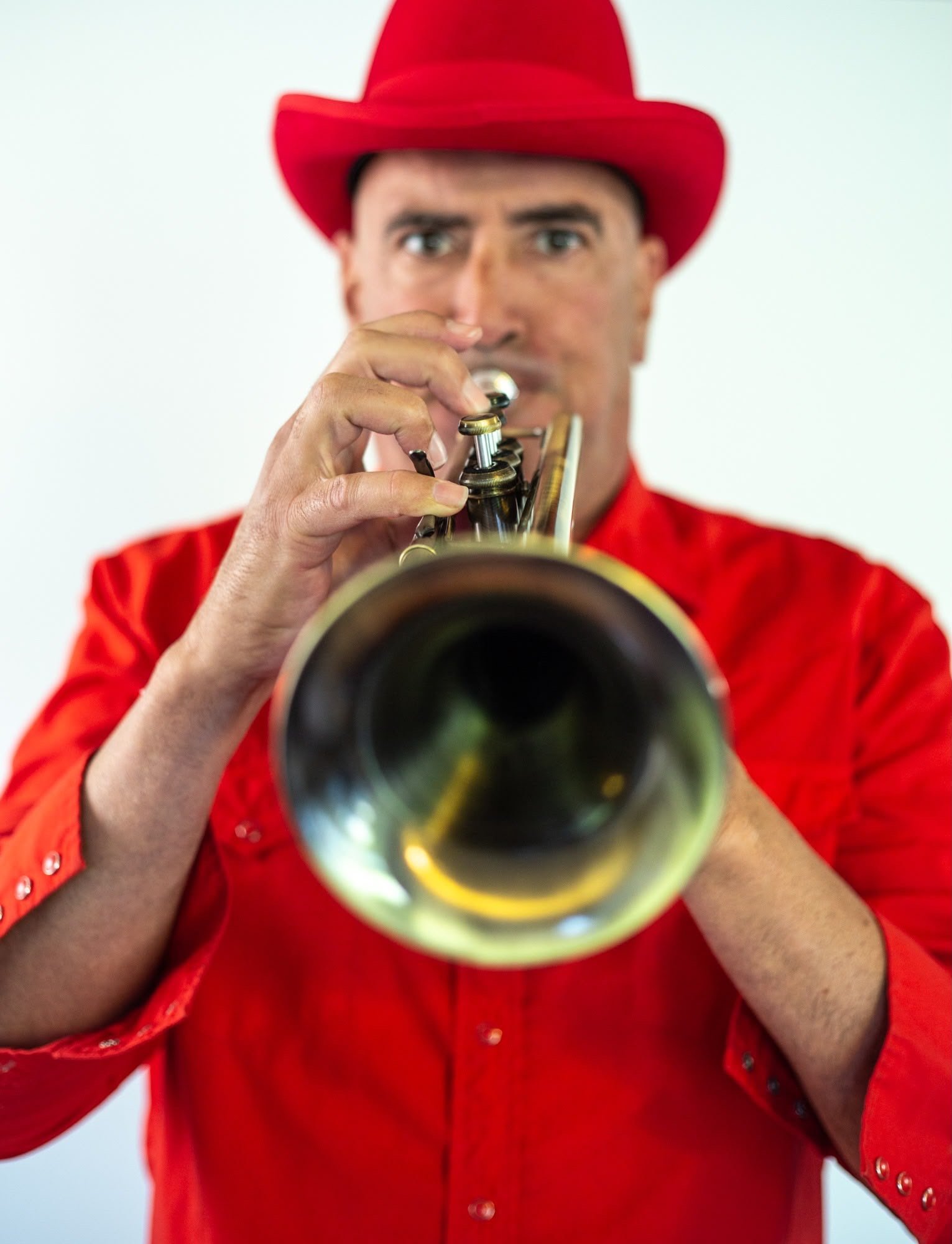 Goyo playing trumpet in a red hat and shirt